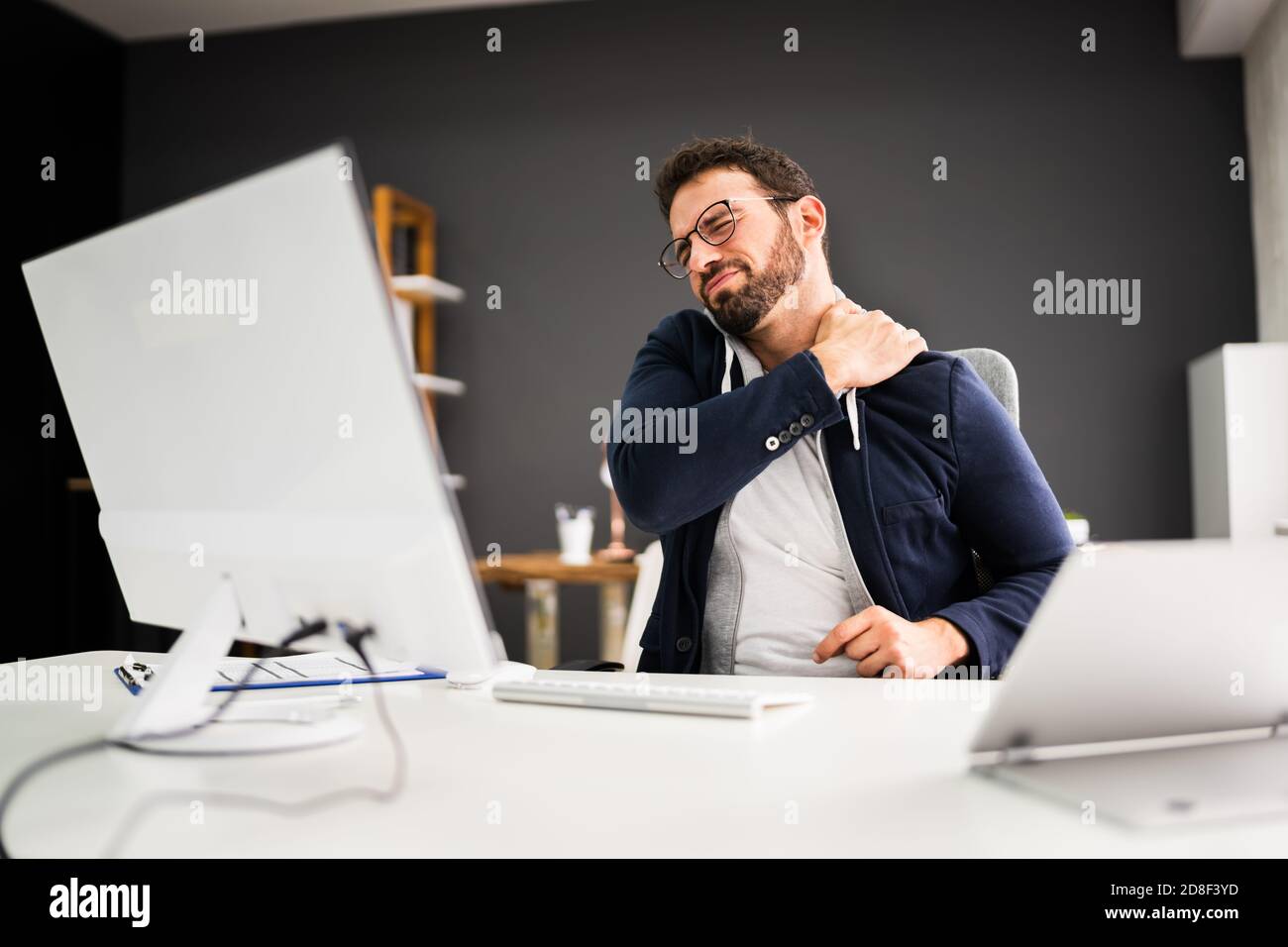 Giovane uomo con dolore alla spalla teso. Problema di postura dell'ufficio Foto Stock