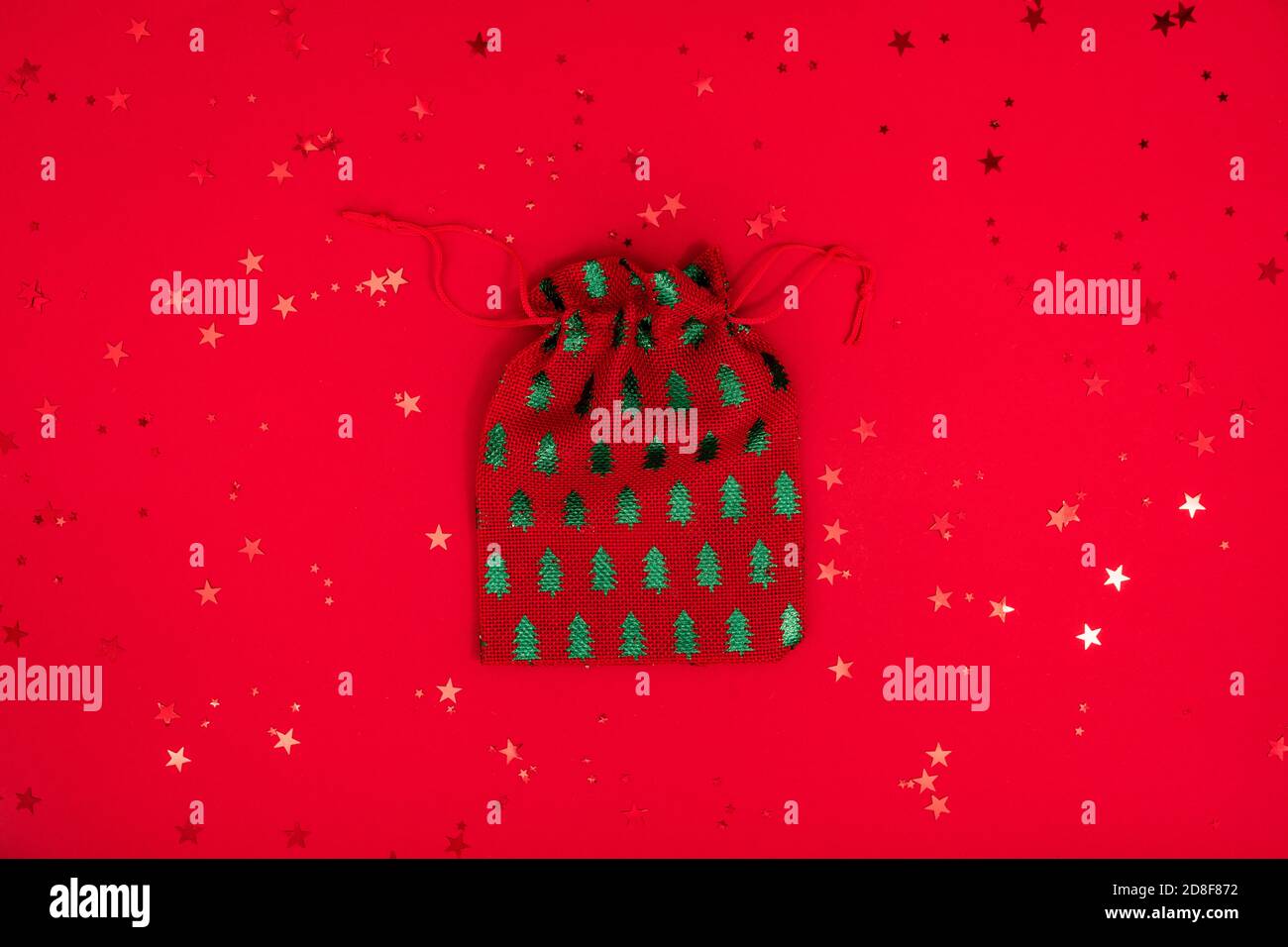 Borsa di Natale giocattolo composizione minima. Decorazioni tessili natalizie su superficie rossa. Vista dall'alto, disposizione piatta Foto Stock