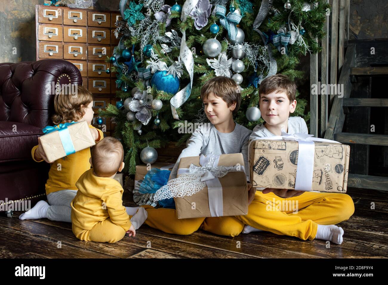 Felici i fratelli bambini che aprono i regali davanti all'albero di Natale.  Tempo di Natale. Concentratevi sul bambino Foto stock - Alamy