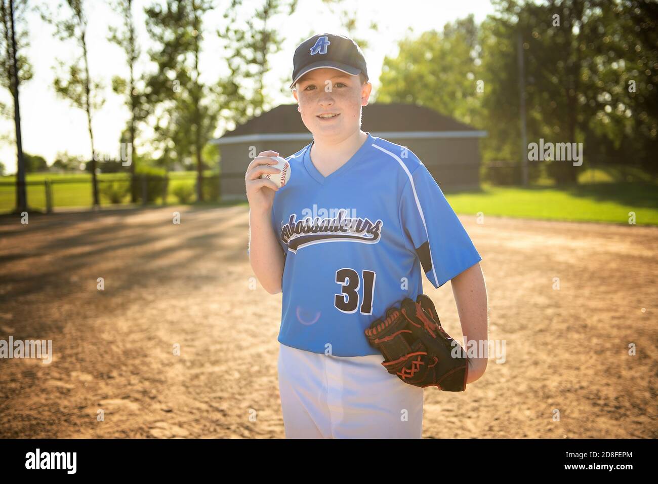 Un giocatore di baseball per bambini in piedi sul parco giochi Foto Stock