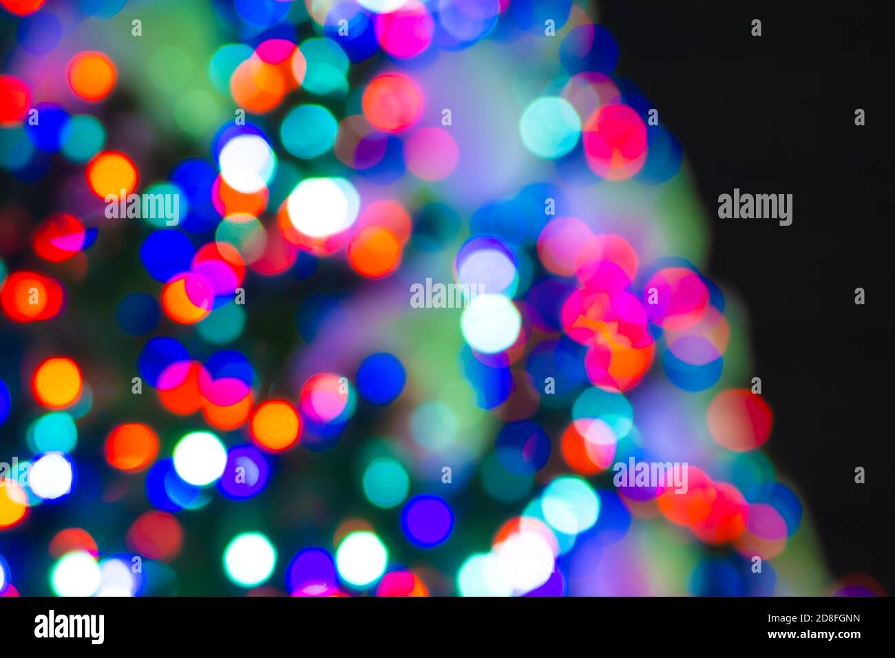 Luci calde spaziate dell'albero di Natale contro il cielo notturno, sfondo non focalizzato Foto Stock