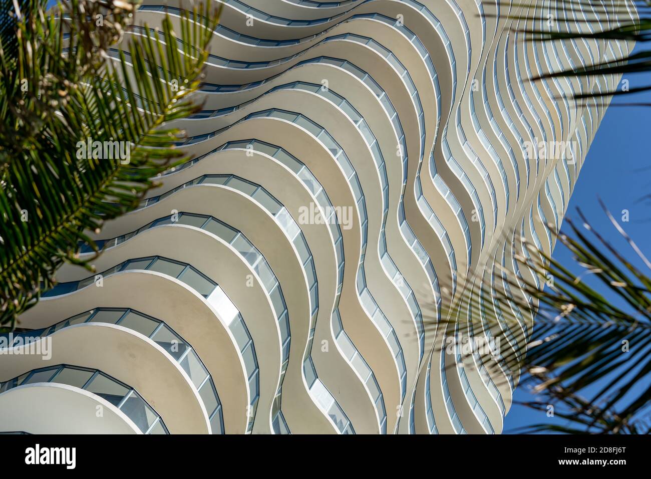 Edificio dal design ondulato con fronte di palme tre in primo piano Foto Stock