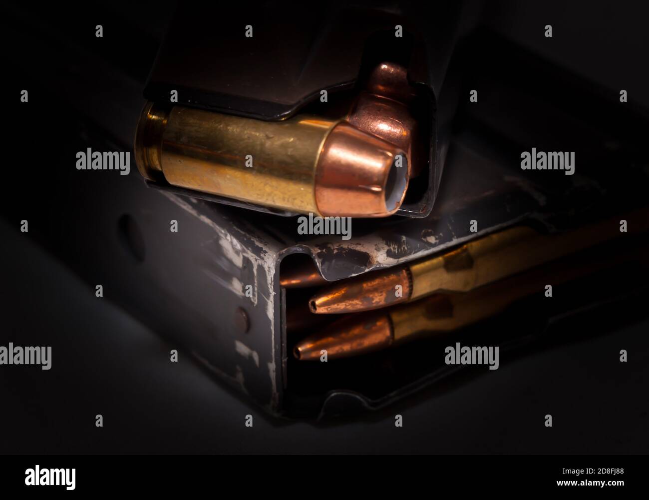 Una rivista di pistole caricata con proiettili a punta cava calibro 0,40 su un caricatore di fucili caricato con calibro .223 punti elenco su sfondo nero Foto Stock