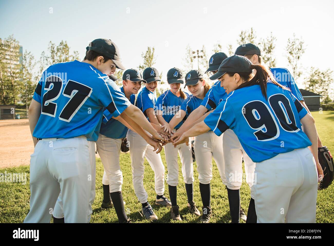 Gruppo di giocatori di baseball in piedi insieme sul parco giochi con celebrazione della mano Foto Stock