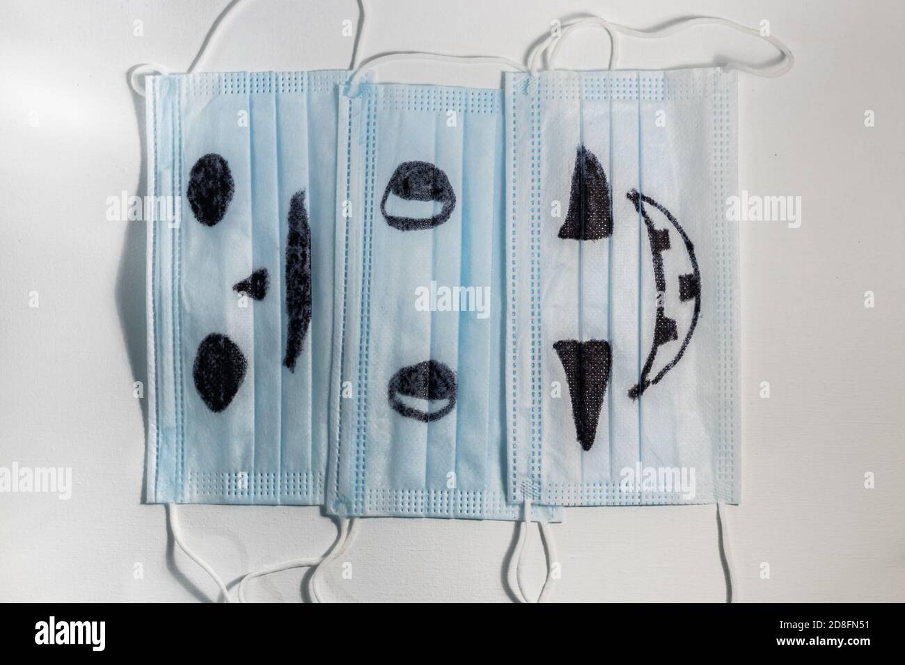 Maschere mediche di protezione blu viso con i volti halloween paurosi disegnati. Foto Stock