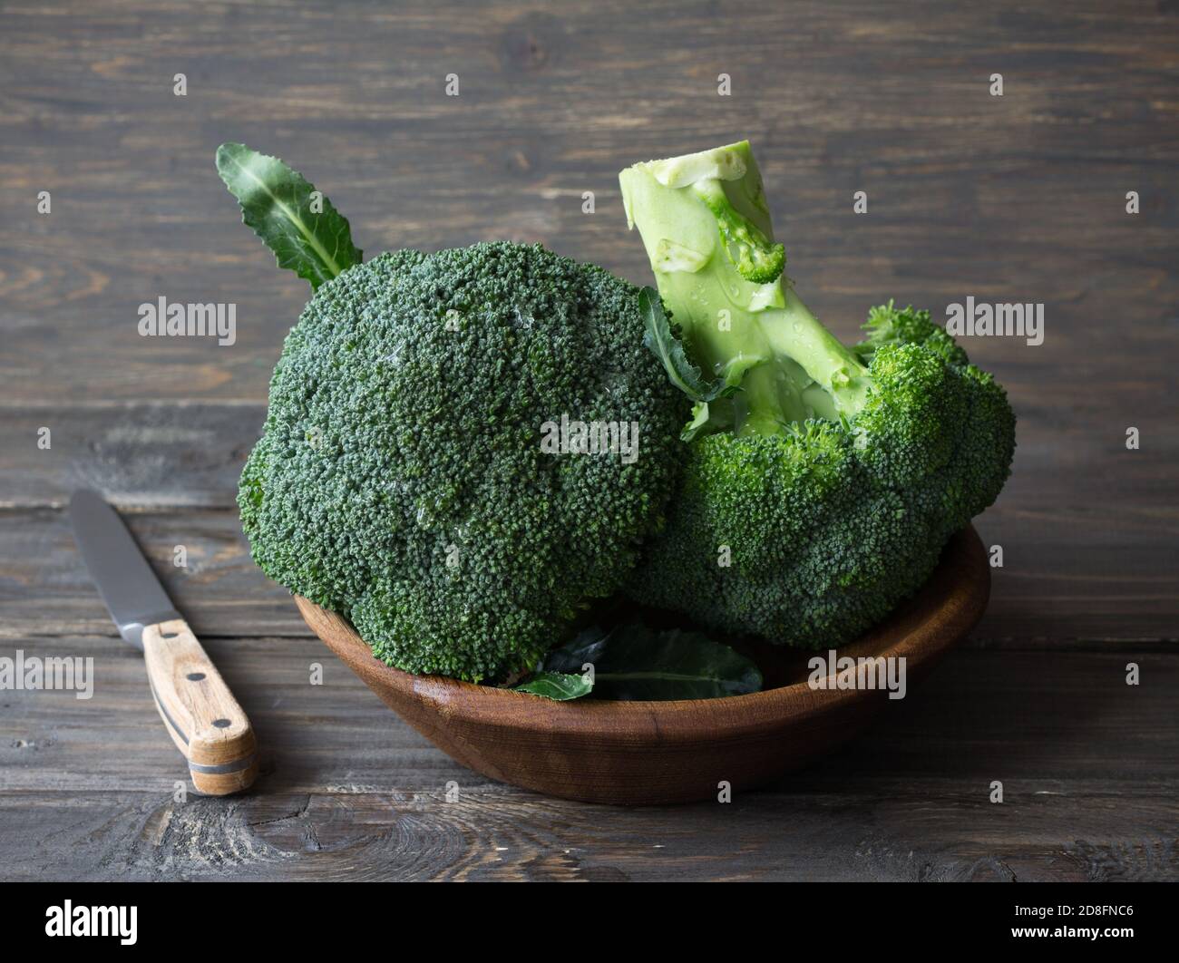 Broccoli freschi in una ciotola di legno su tavolo di legno, stile rustico Foto Stock