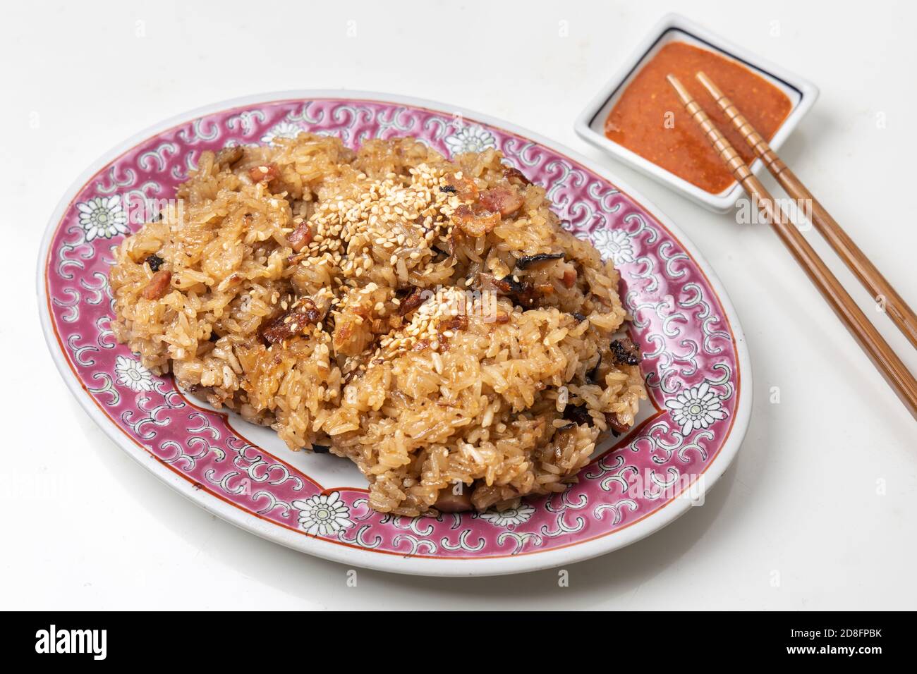 Riso glutinoso cinese tradizionale con maiale, salsiccia, funghi e sesamo con salsa di peperoncino come immersione. Foto Stock