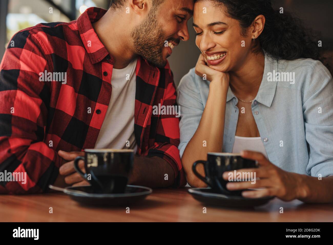 Una coppia affettuosa che ha un caffè in una data in un caffè. Una coppia amorosa che si siede al caffè toccando le fronte e sorridendo. Foto Stock