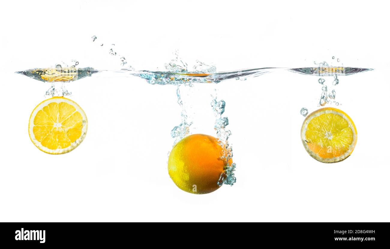 le arance fresche si tuffano in acqua su sfondo bianco Foto Stock