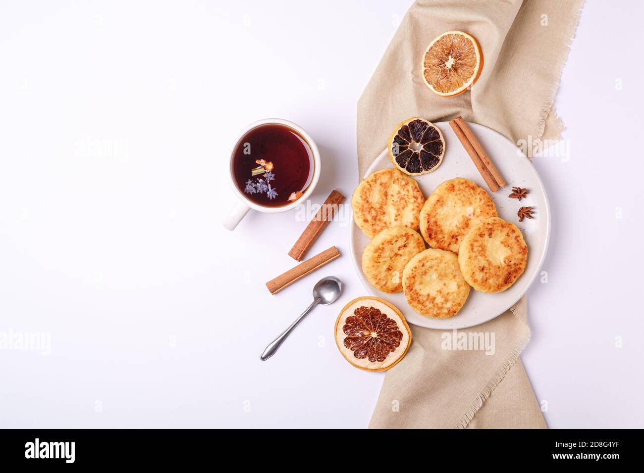 Frittelle di formaggio cottage con tè nero aromatico caldo, umore della colazione di Natale con anice e cannella su sfondo bianco, vista dall'alto Foto Stock
