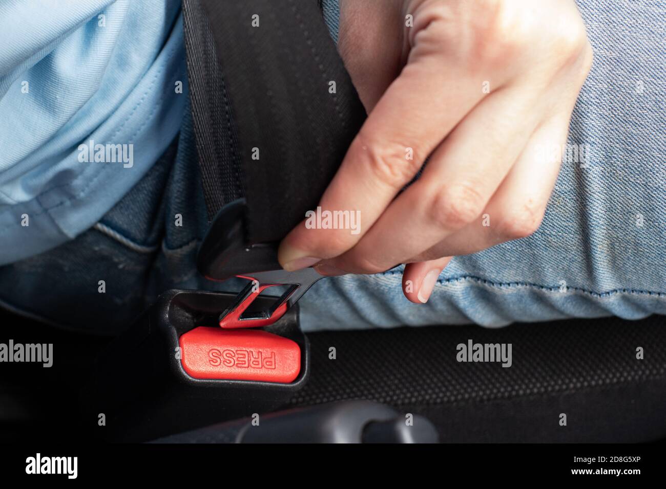 Primo piano del montaggio della cintura di sicurezza di un giovane uomo in un'automobile, un conducente femmina allaccia una cintura di sicurezza Foto Stock