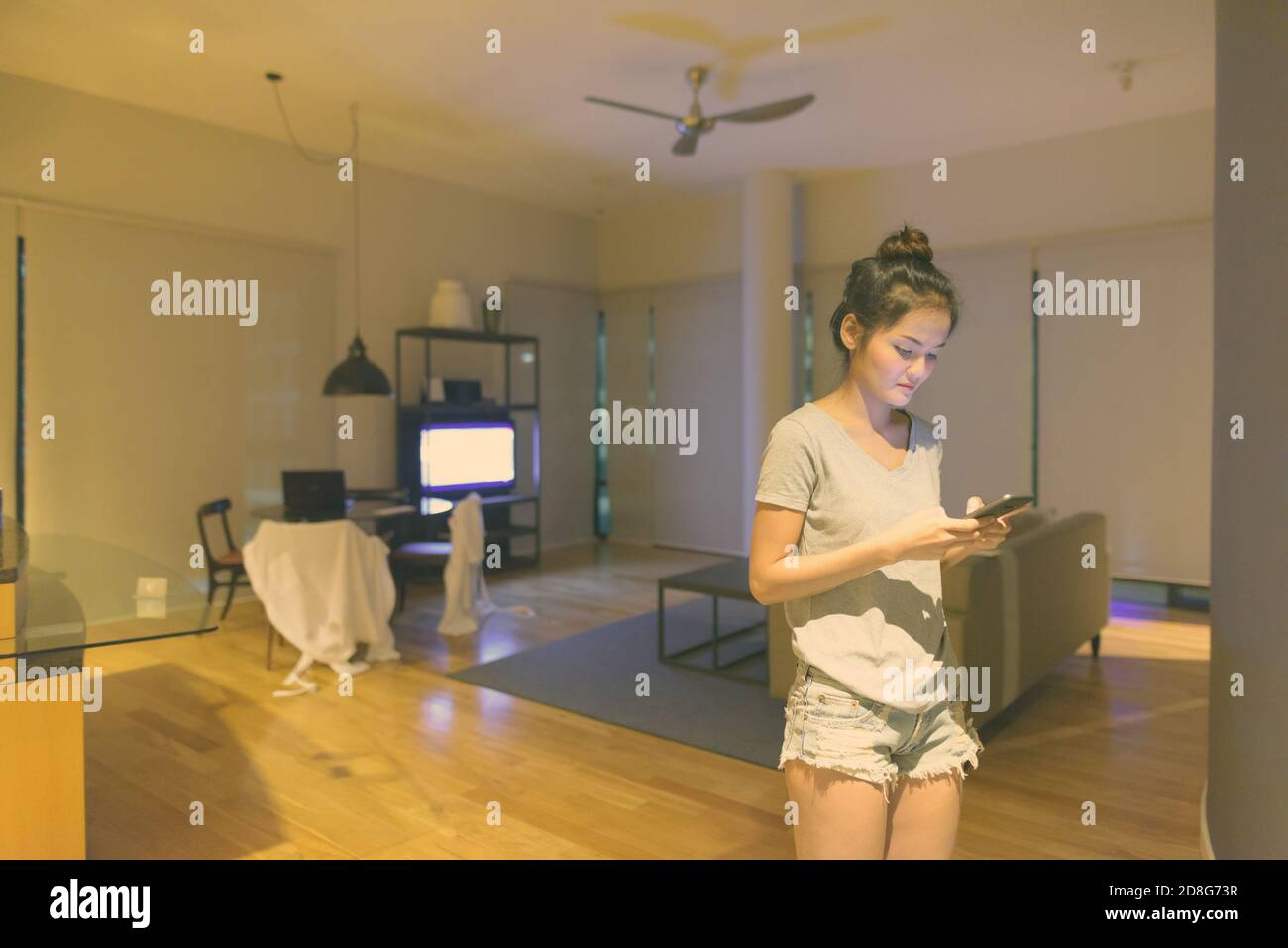 Giovane bella donna asiatica rilassante nella stanza vivente Foto Stock