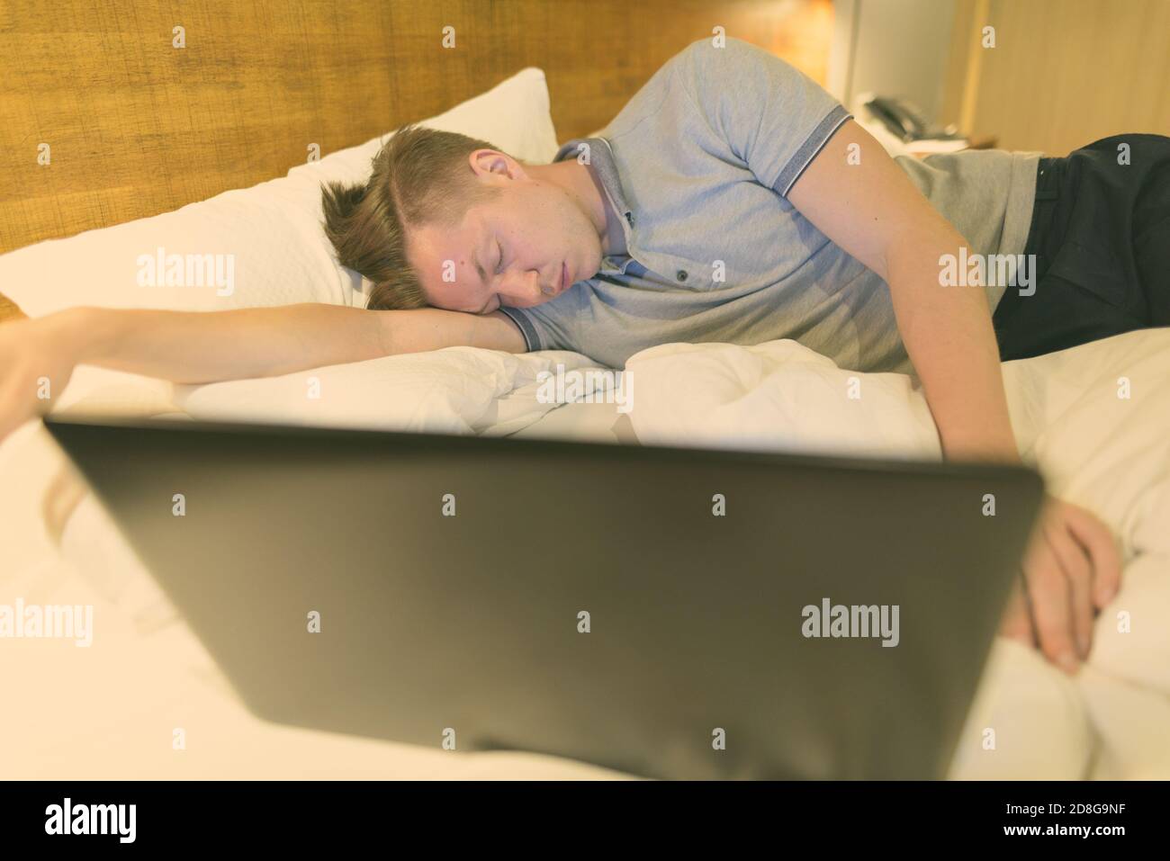 Giovane bell'uomo che usa il computer portatile mentre è comodo in camera da letto Foto Stock