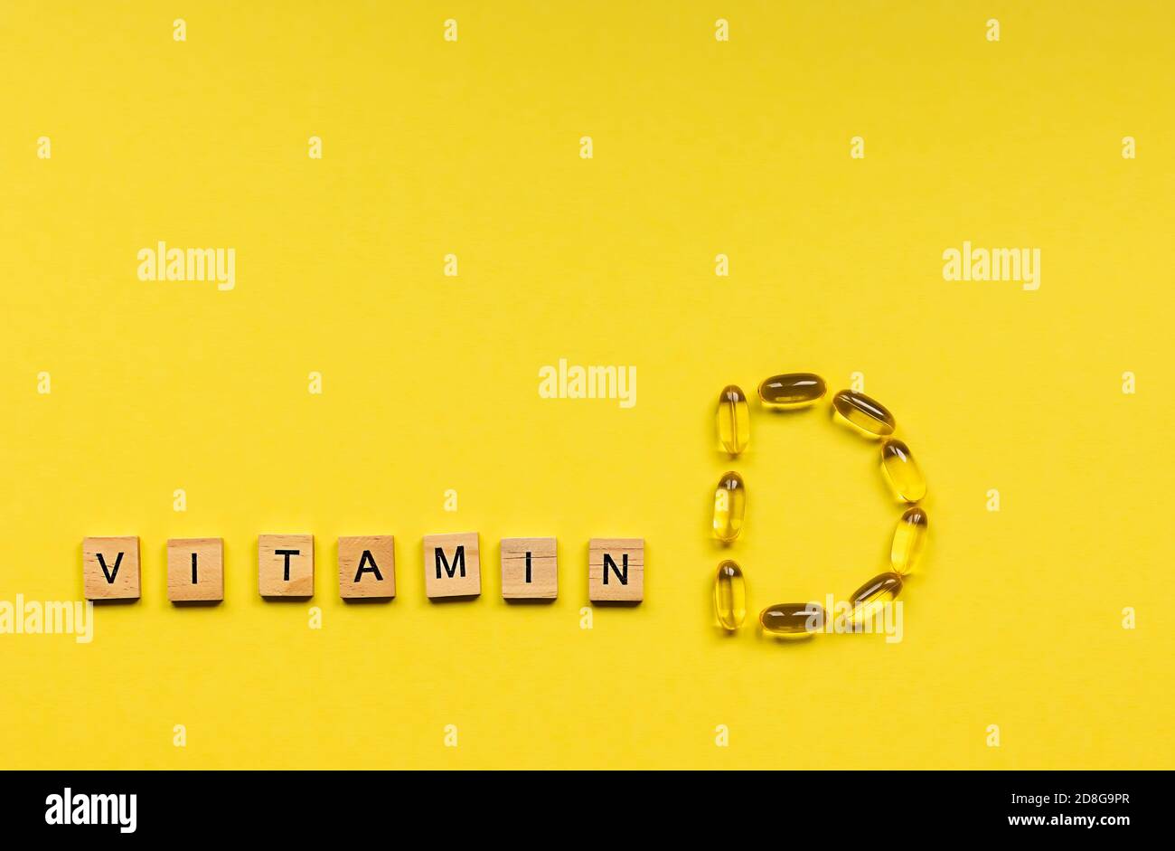 Capsule gialle sotto forma di lettere D e. Cubetti di legno con lettere Vitamina Foto Stock