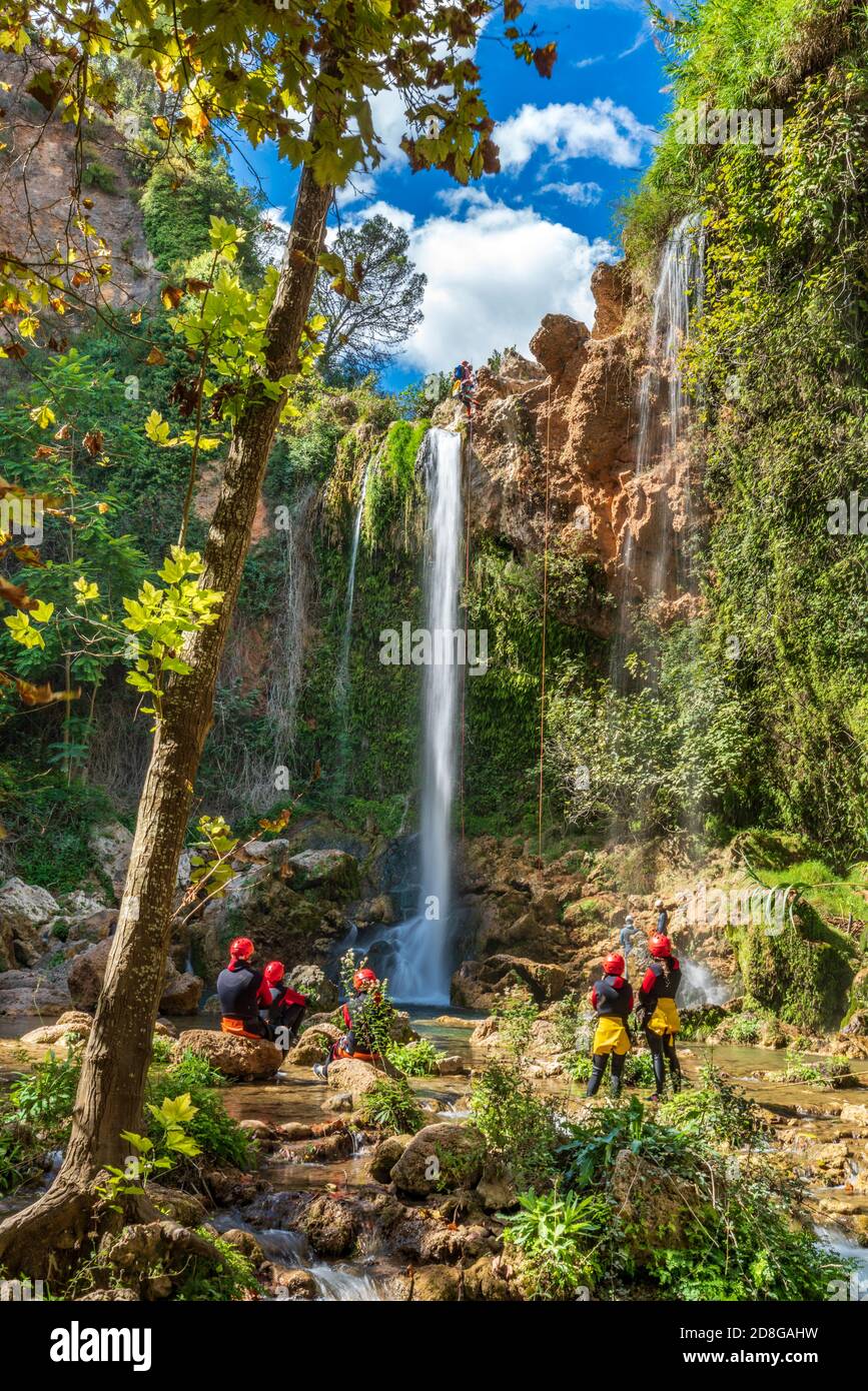 Un grande gruppo di persone si gode la discesa a cascata usando le corde Foto Stock