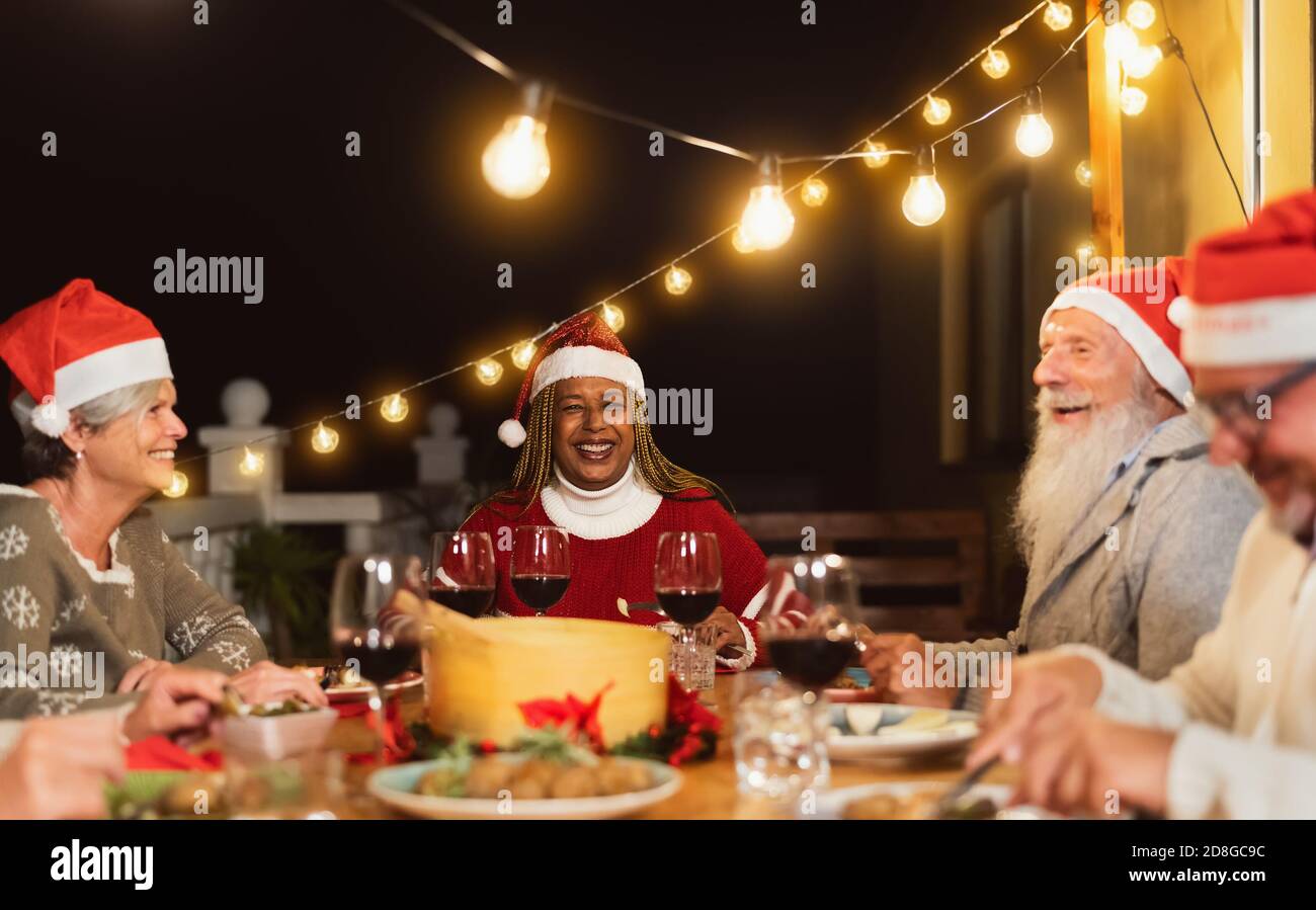 I buoni amici senior cenano insieme durante le feste di Natale festa nel patio della casa Foto Stock