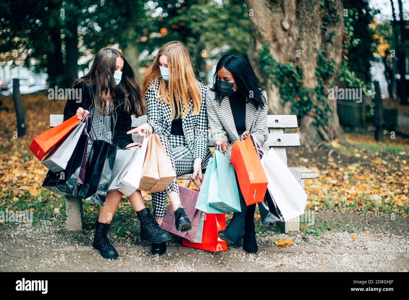 donna shoppers outdoor indossare una maschera protettiva e divertirsi insieme. Amici che si aggingono in un periodo pandemico. Nuovo concetto normale. Foto Stock