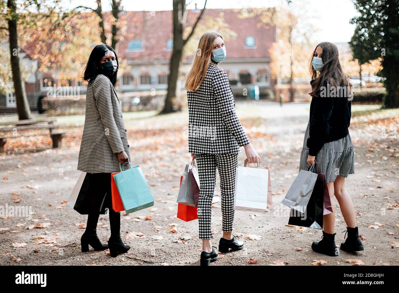 gruppo di donne di razza mista con maschere facciali e. tenere borse per la spesa Foto Stock