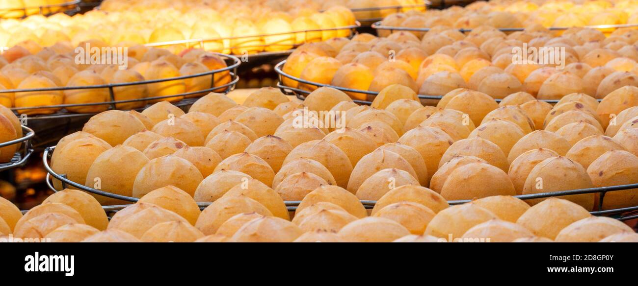 Facendo il processo di sole che espositing che asciuga il persimmon sbucciato essiccato in un setaccio, concetto di cibo conservato d'autunno. Foto Stock