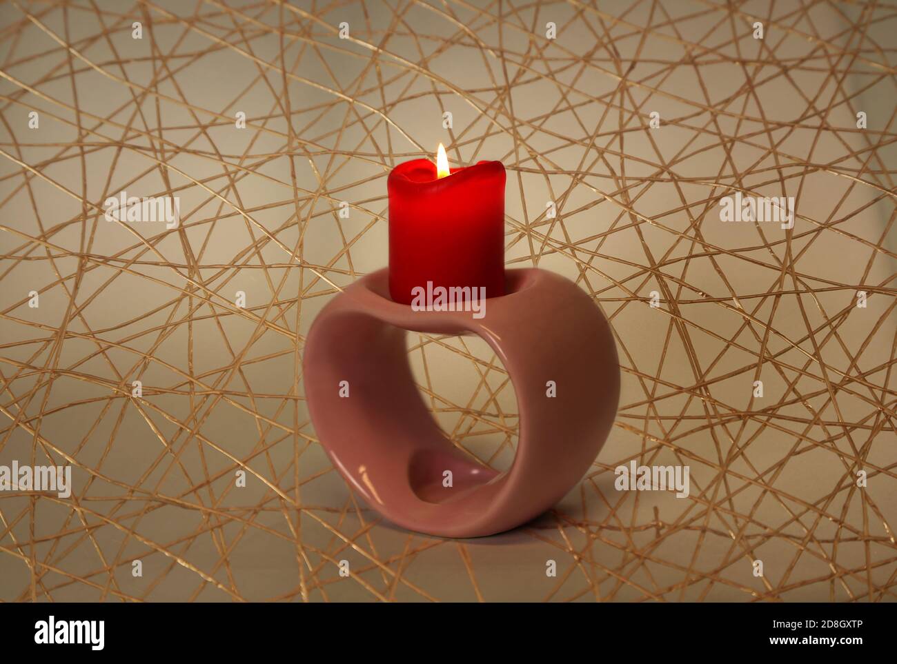 Closeup di un portacandele per il giorno di San Valentino, su uno sfondo pieno di archi d'oro Foto Stock