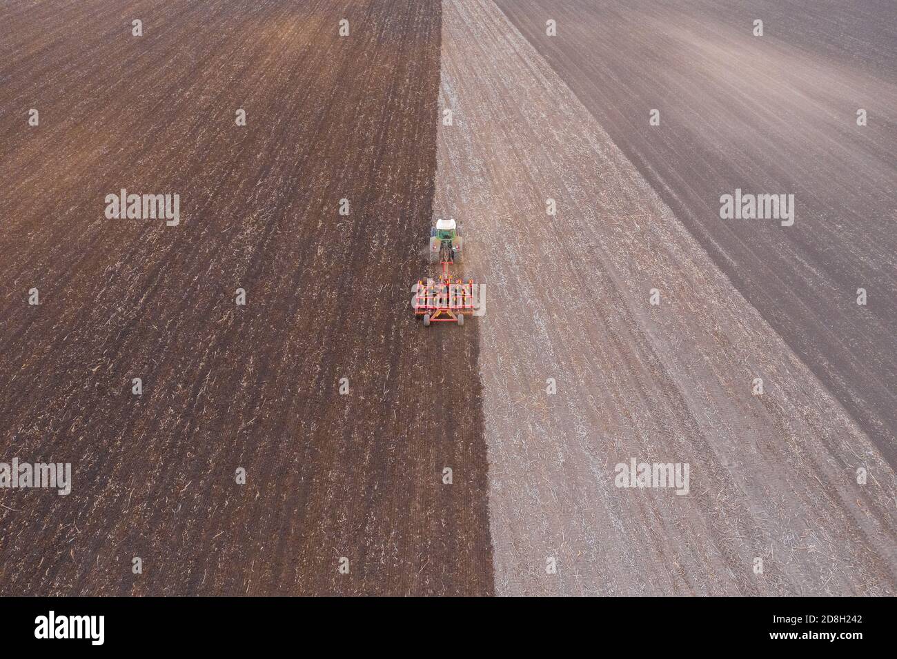 Lajoskomarom, Ungheria - Vista aerea del campo di coltivazione di trattori rossi in campagna dopo la mietitura. Concetto di azienda agricola, lavori agricoli in terreni agricoli. Foto Stock