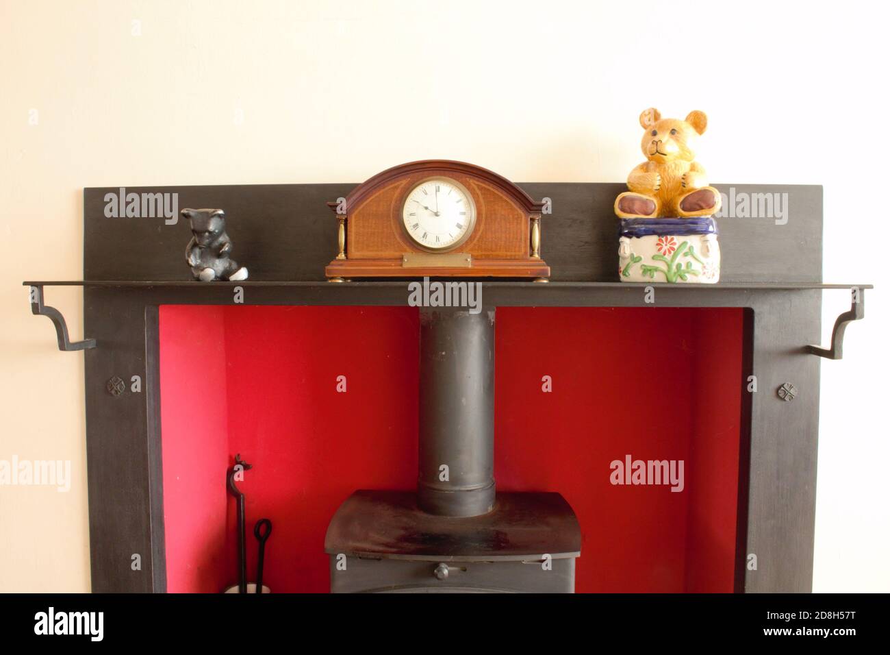 Mantelpiece con orologio vecchio, ornamenti teddy e bruciatore di tronchi sotto Foto Stock