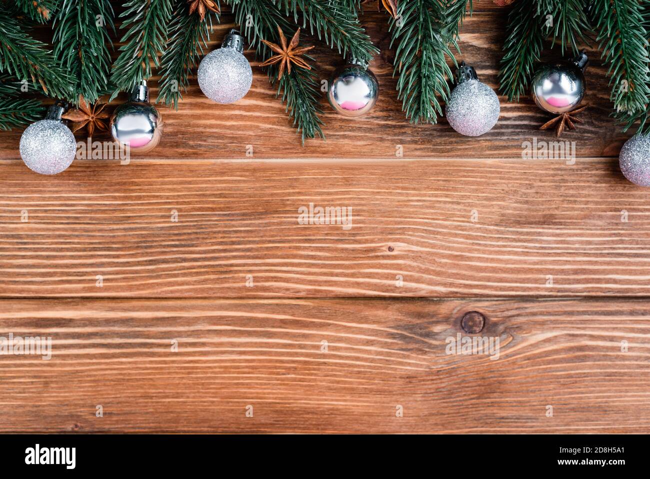 Vista dall'alto di rami di pino, baubles e stelle di anice su sfondo di legno marrone, concetto di nuovo anno Foto Stock