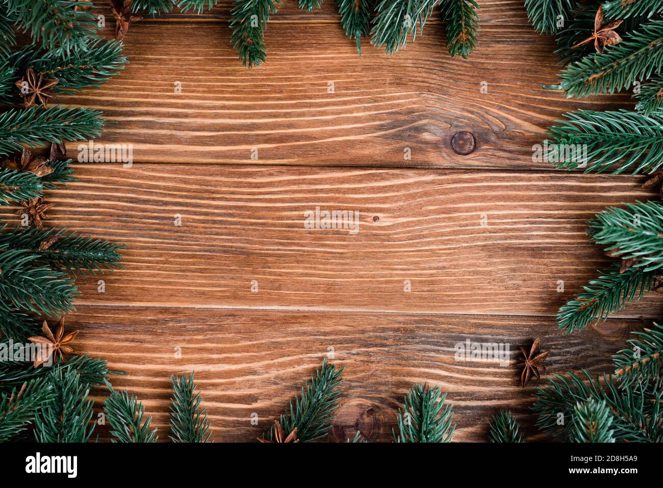 Piatto con rami di pino e stelle di anice su sfondo di legno marrone, concetto di nuovo anno Foto Stock