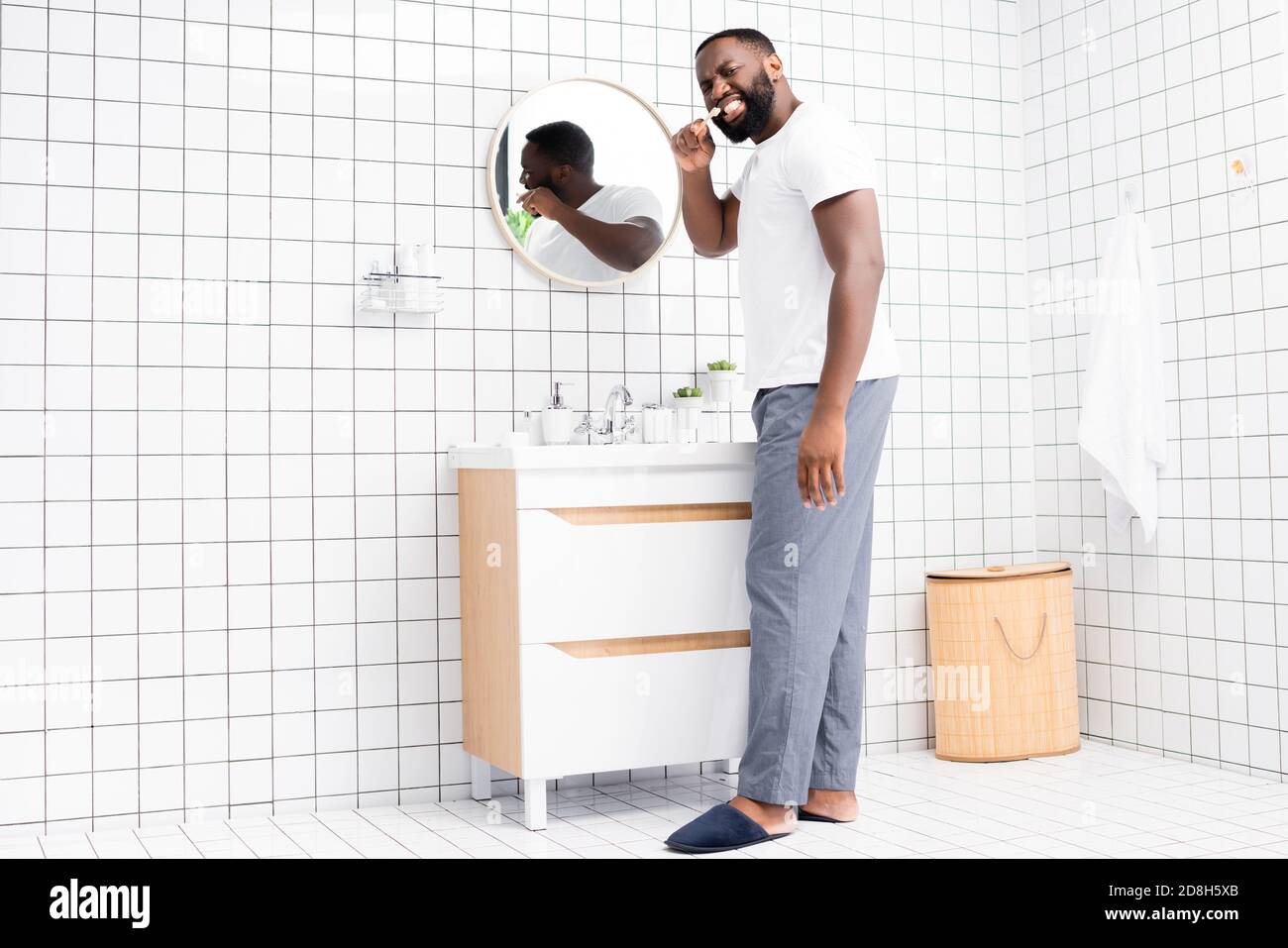 tutta la lunghezza di uomo afro-americano spazzolando i denti e guardando indietro Foto Stock