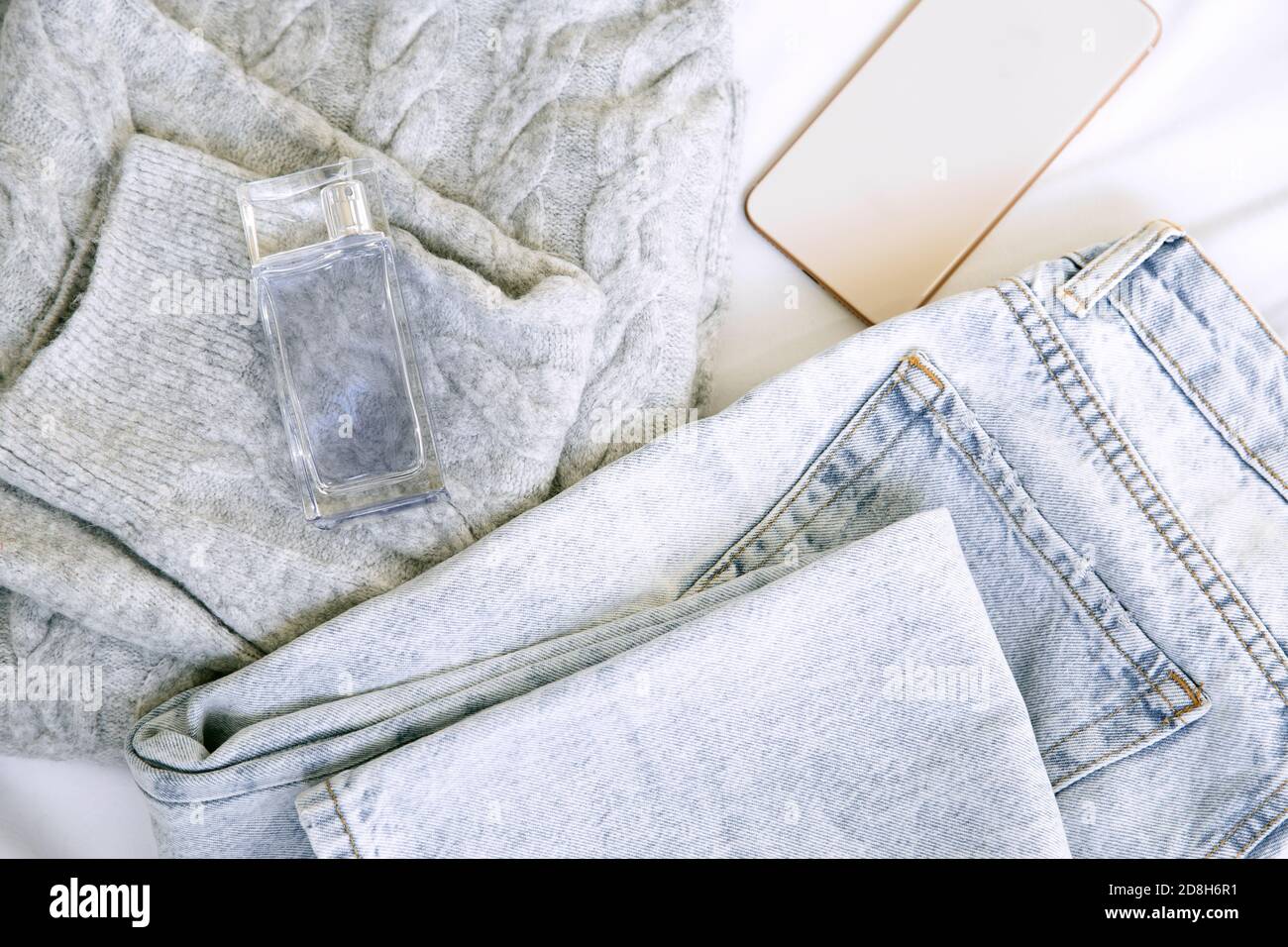 Jeans casual blu chiaro e felpa accogliente con oro chiaro monile telefono e profumo blu Foto Stock