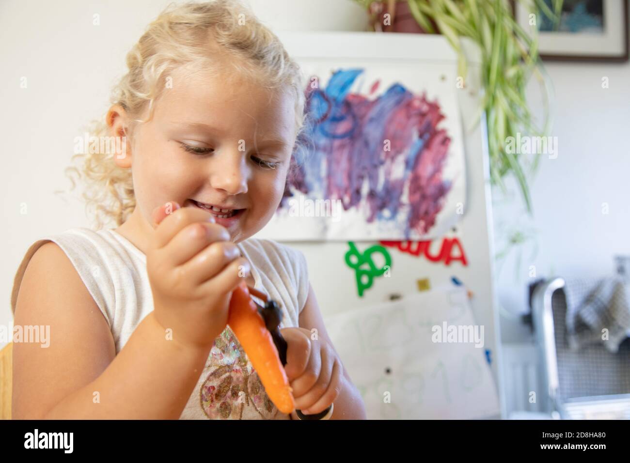 Una ragazza di tre pelette una carota indipendentemente in lei cucina domestica Foto Stock