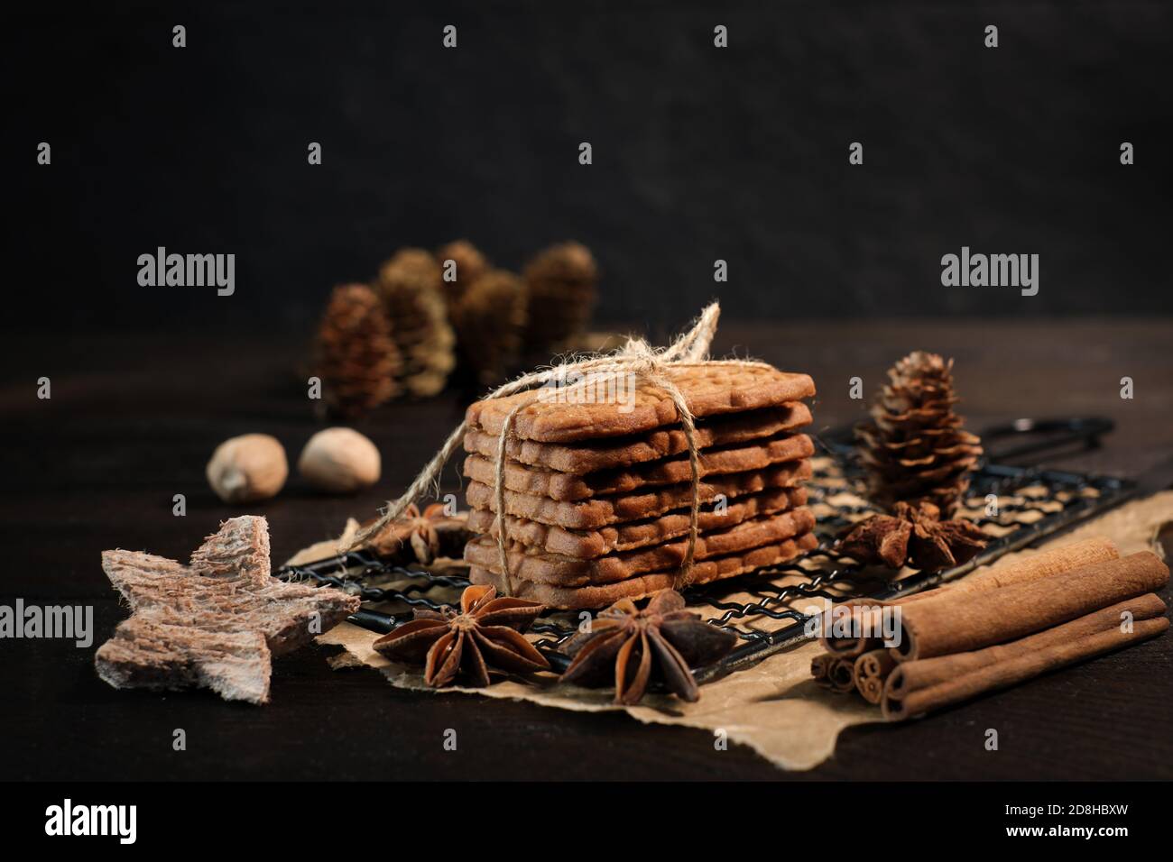 Macchie accatastate con nastro di imballaggio avvolto su una griglia di raffreddamento nera, decorata con stelle di legno, bastoncini di cannella e stelle di anice, sullo sfondo f Foto Stock