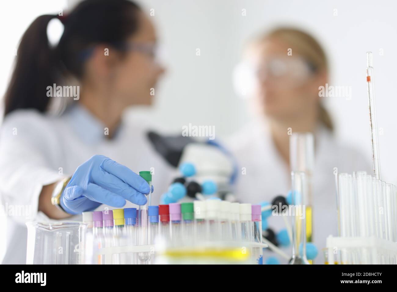 Le donne scienziati tengono le provette in vetro nei guanti in sostanze chimiche primo piano del laboratorio Foto Stock