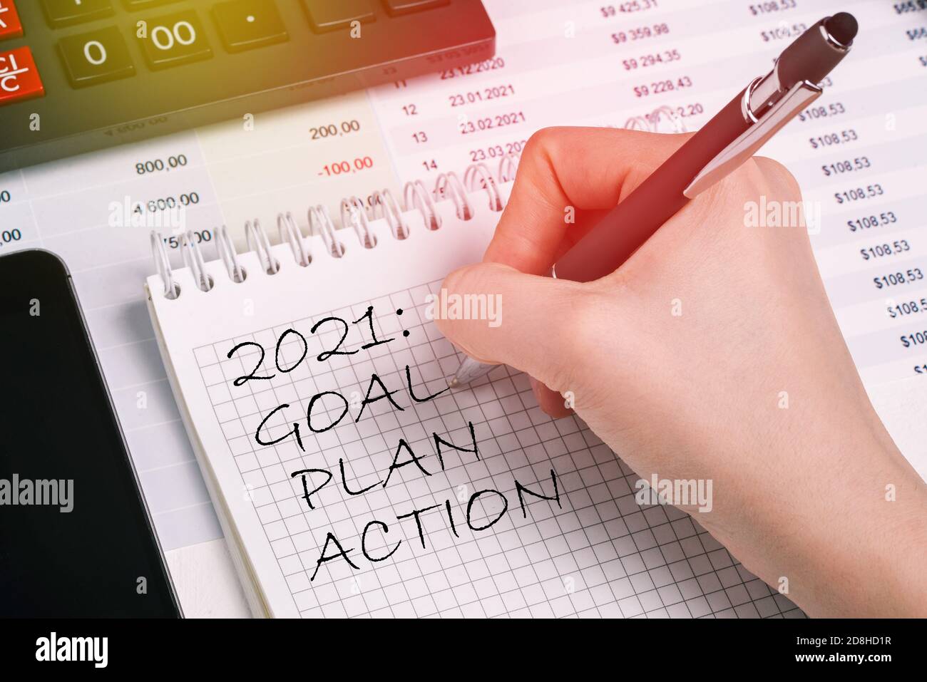 Il lavoratore di ufficio scrive un elenco per 2021 in un notebook. Concetto di pianificazione, impostazione degli obiettivi. Foto Stock
