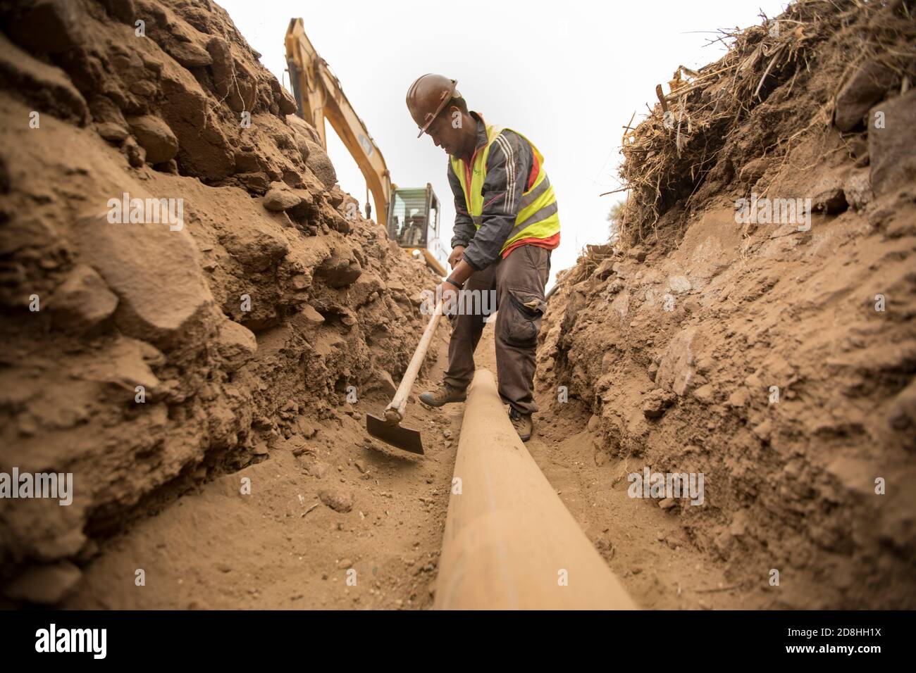 Un lavoratore di costruzione lavora per installare una nuova linea idrica sotterranea sull'isola di Santiago, Cabo Verde. Foto Stock