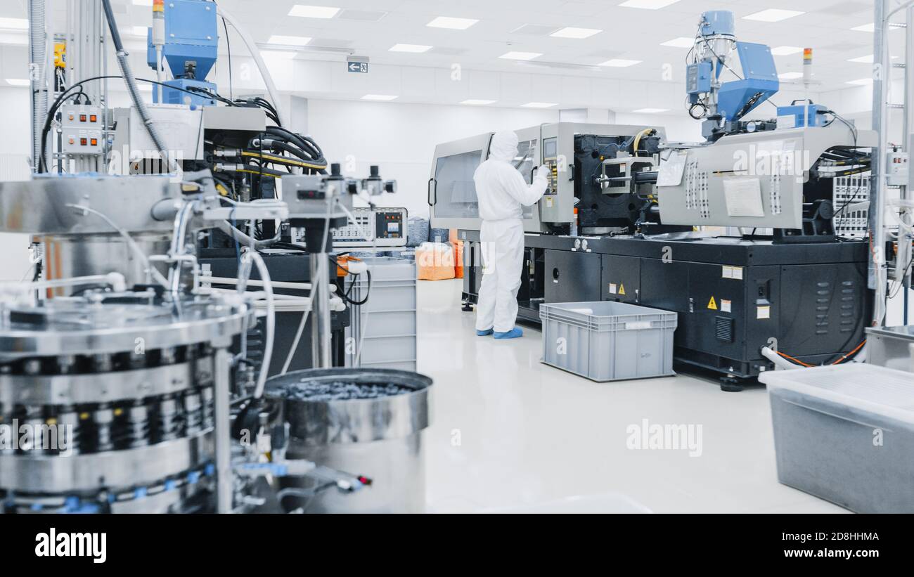 Su uno scienziato di fabbrica in indumenti protettivi sterili lavoro su un moderno industriale 3D macchina di stampa. Farmaceutico, biotecnologico e. Foto Stock