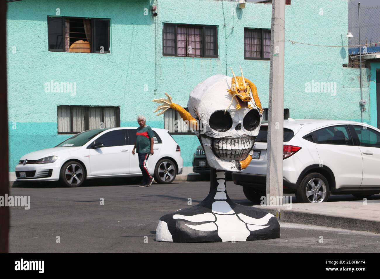 Non esclusivo: CITTÀ DEL MESSICO, MESSICO - OTTOBRE 30: Una persona indossa la maschera mentre cammina davanti a un monumentale cranio fatto di cartone, sono stati messi a decorare Foto Stock