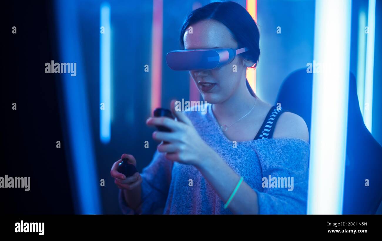 Bella Pro Gamer Girl indossare Virtual Reality Headset gioca in Online Video Game, gesturing utilizzando Controller. Colori retro Neon in camera. Foto Stock