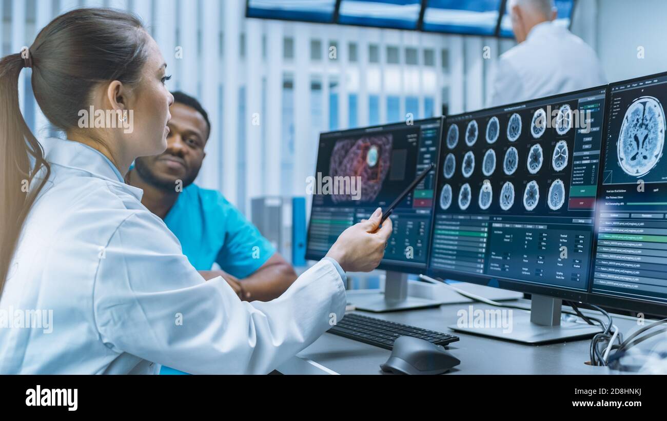 Medico scienziato e chirurgo che discute immagini TAC Brain Scan su un personal computer in laboratorio. Neurologi neuroscienziati in futuristico Foto Stock