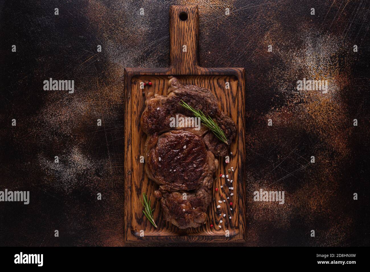 Bistecca di manzo alla griglia con spezie su tavola di legno, vista dall'alto. Foto Stock