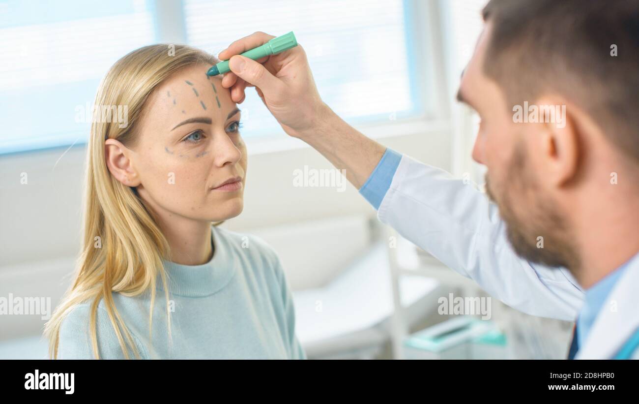 Sopra il colpo della spalla di un chirurgo cosmetico di plastica disegna le linee su un volto di un modello femminile bello per l'operazione di Facelift. Foto Stock