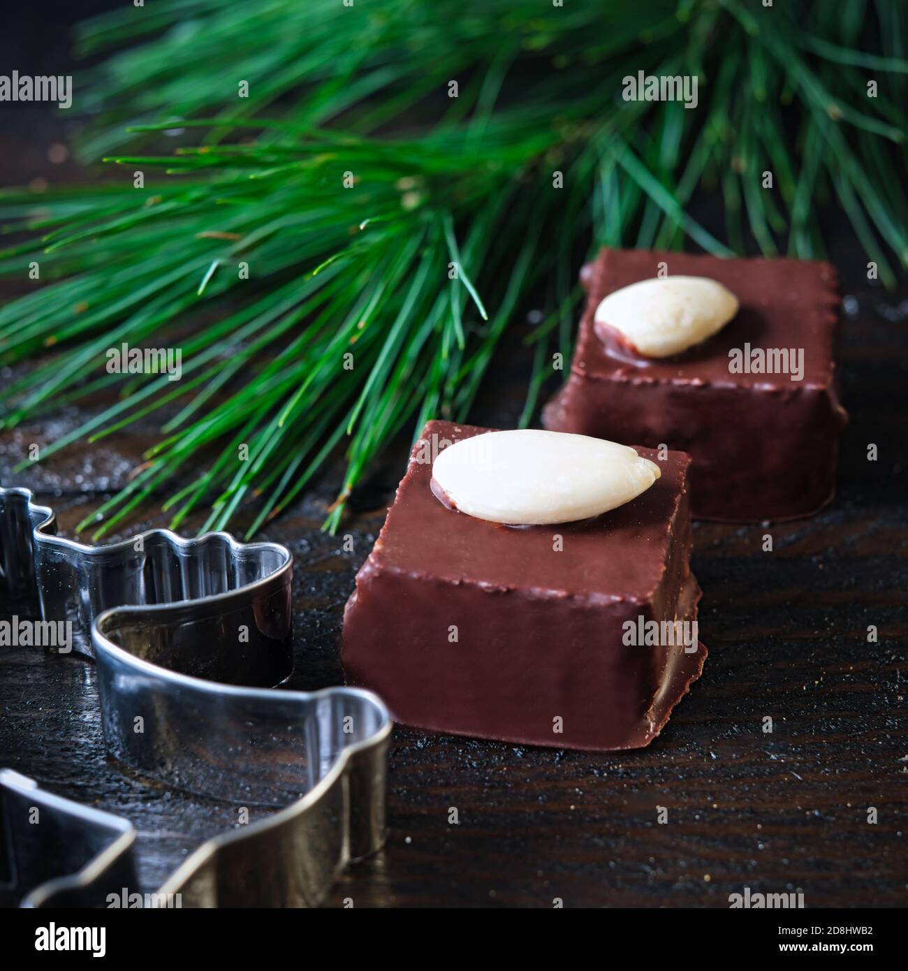 Marzipancubes con glassa di cioccolato su griglia nera, decorata con ramo di  pino, bastoncini di cannella e stelle di anice, coni di abete Foto stock -  Alamy