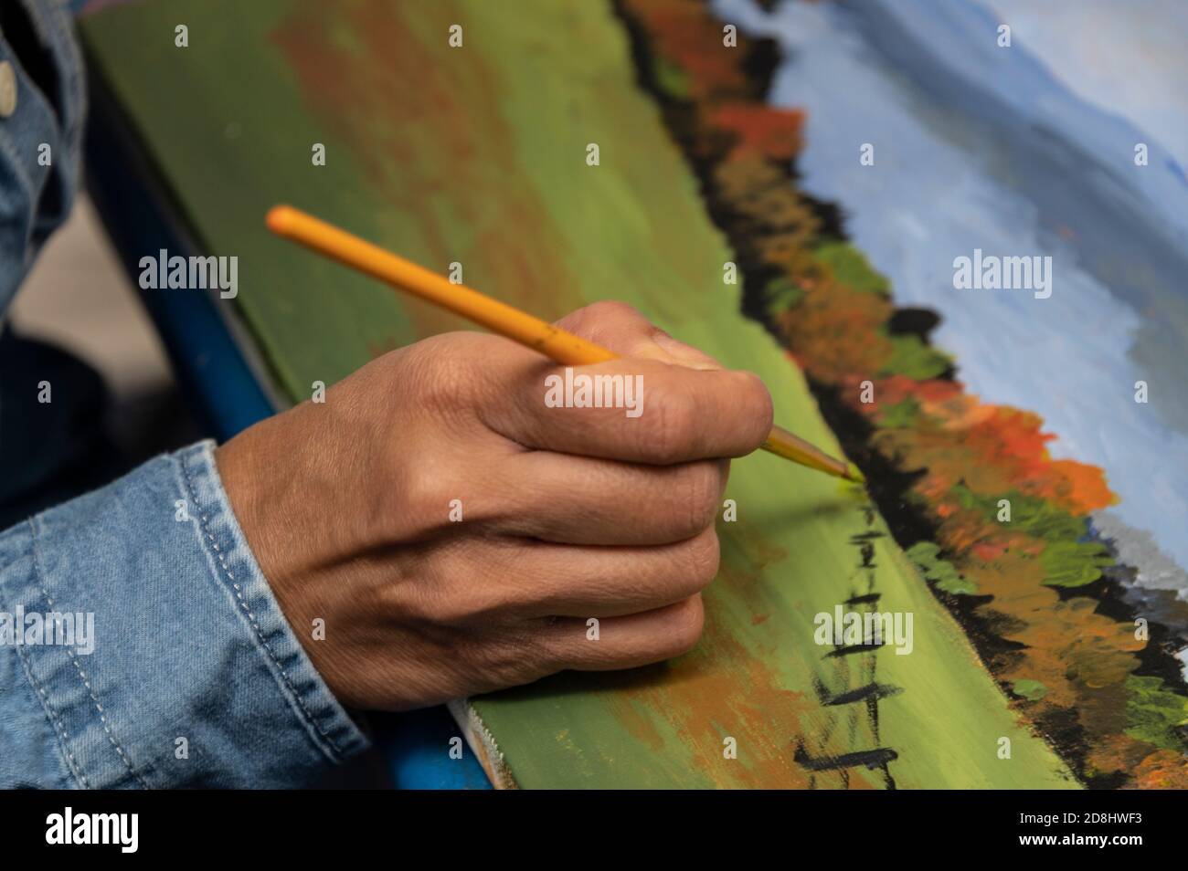 Un artista studentesca che usa il suo pennello, dipingendo un quadro usando vernici acriliche durante una lezione d'arte, Inghilterra Foto Stock