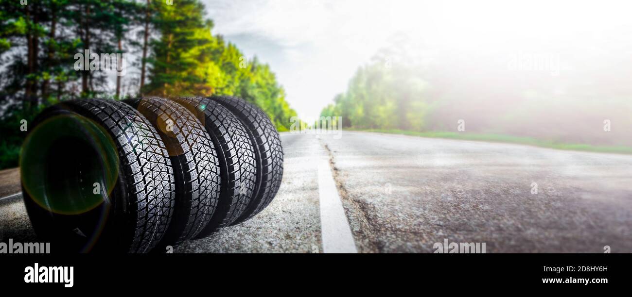 Cambiare una macchina stagionale pneumatico estate strada forestale con alberi sfondo. Sostituzione per pneumatici invernali. Banner di vendita off. O sfondo automeccanico Foto Stock