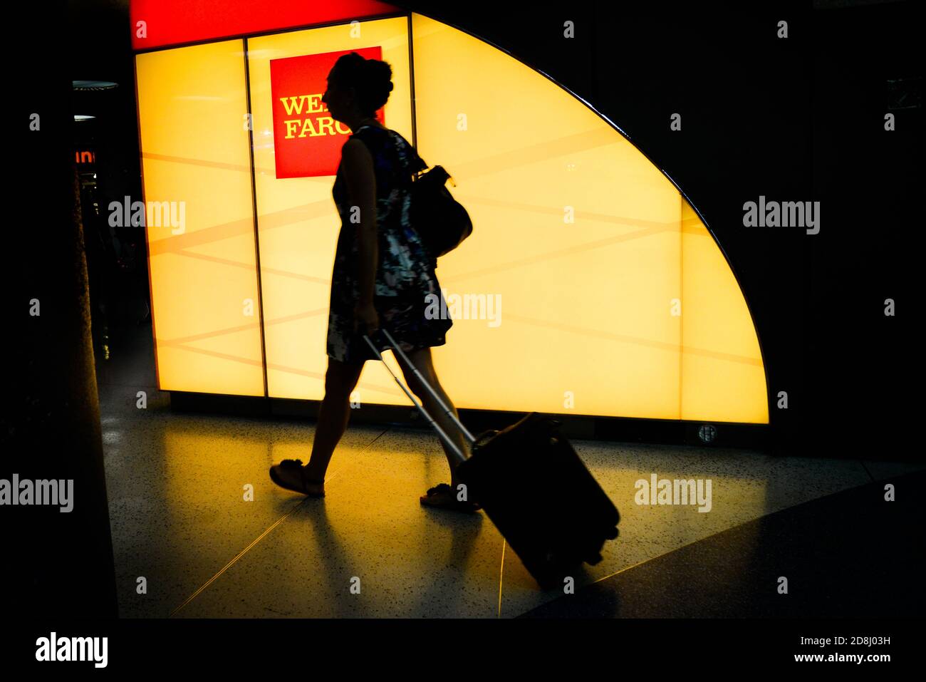 I viaggiatori camminano oltre il logo Wells Fargo a Penn Station, New York City, USA. Foto Stock