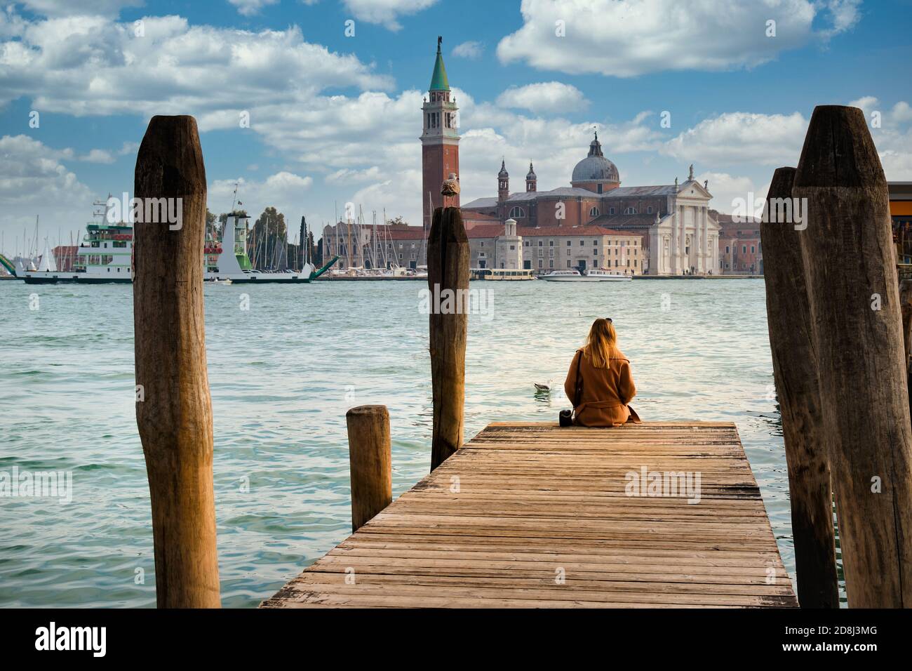 Vacanze a Venezia. Vista posteriore di bella ragazza che gode di vista sulla Laguna di Venezia con l'isola di San Giorgio maggiore e gondole Foto Stock