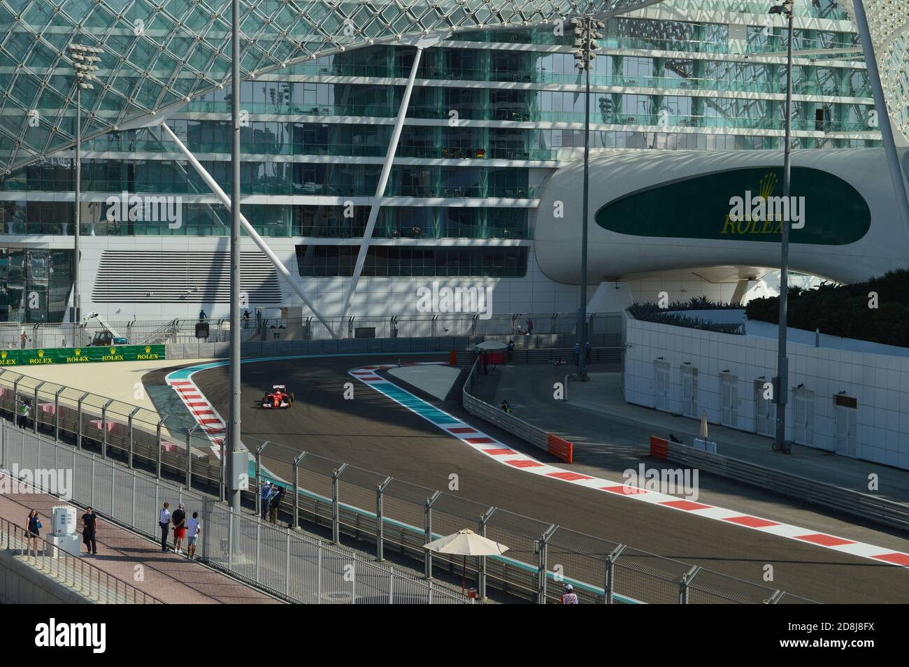 Una vettura da corsa di Formula 1 che attraversa il circuito sotto il ponte, con lo Yas Hotel sullo sfondo. Foto Stock