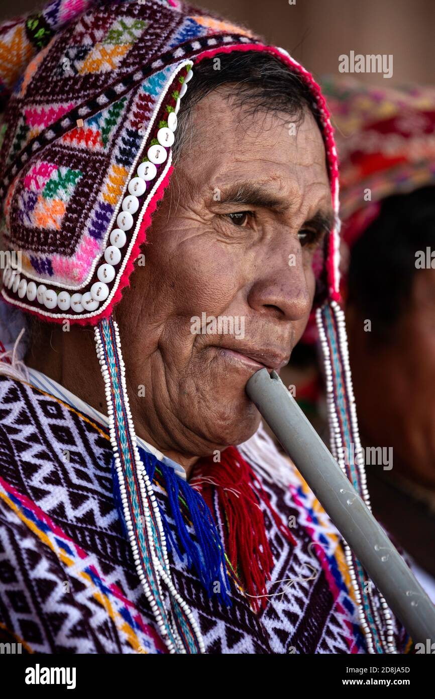 Quechua uomo indossando costume tradizionale (compreso il chullo) e suonando flauto, Pisac Domenica mercato, Pisac, Perù Foto Stock