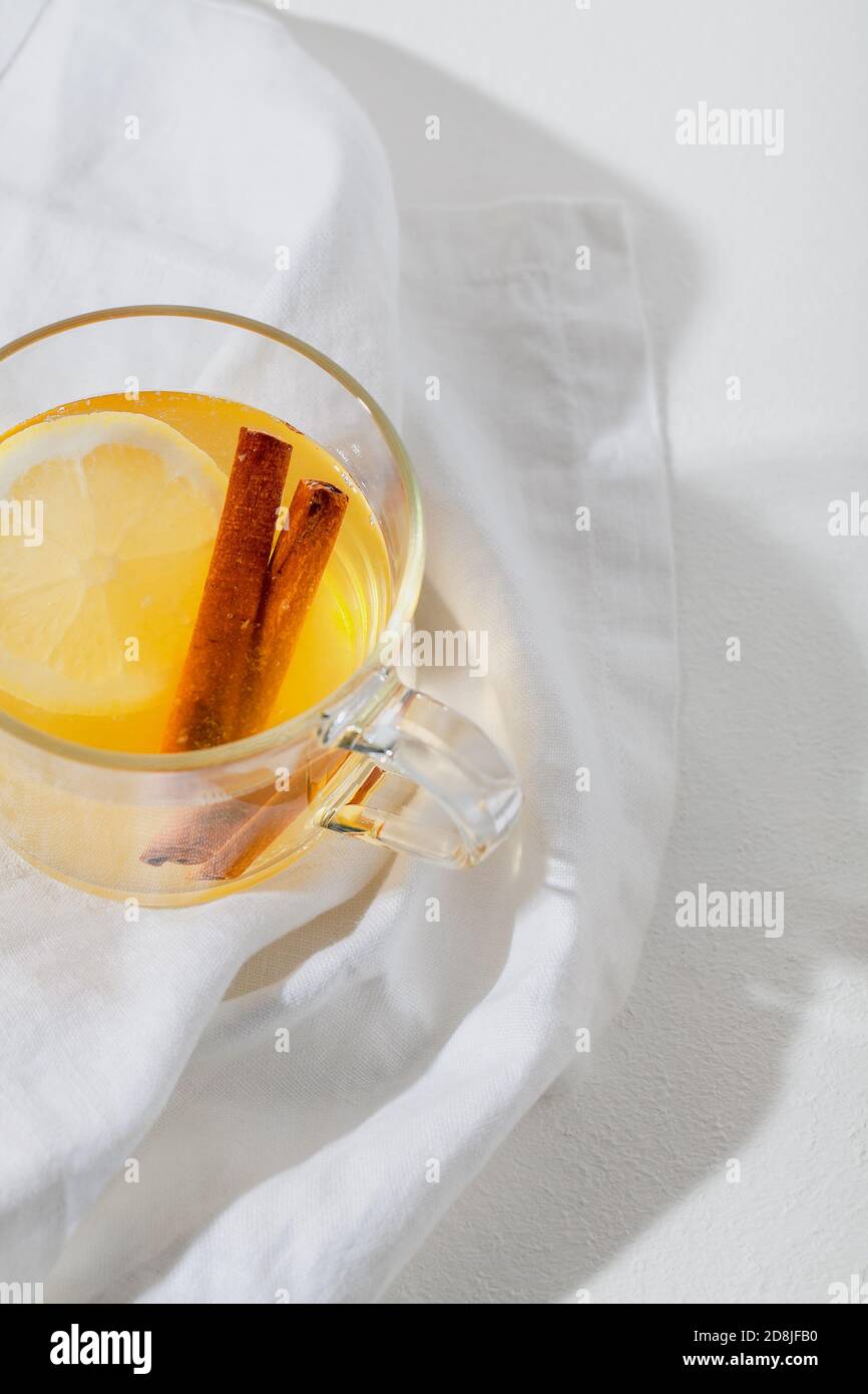 Bevande calde Toddy cocktail con limone, miele e cannella bastone in vetro su sfondo bianco. Bevanda invernale speziata Foto Stock