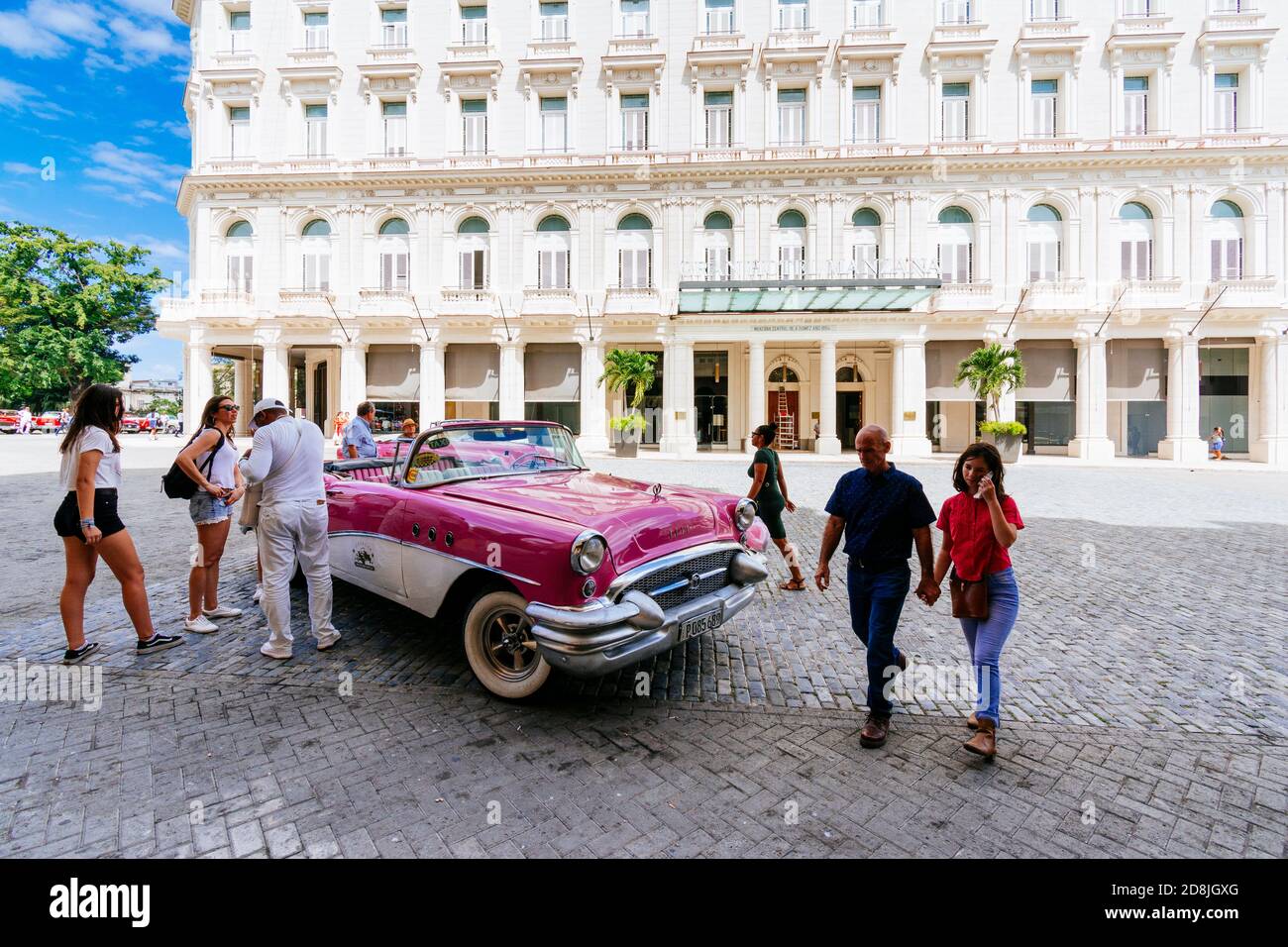 I turisti si trovano vicino a un taxi - almendrón - di fronte al Gran Hotel Manzana Kempinski. L'Avana. Cuba, America Latina e Caraibi Foto Stock